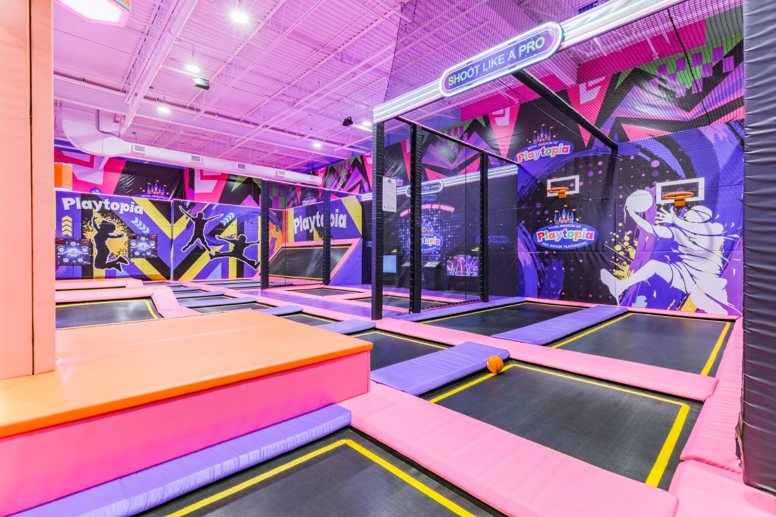 Indoor trampoline basketball court with padded hoops.