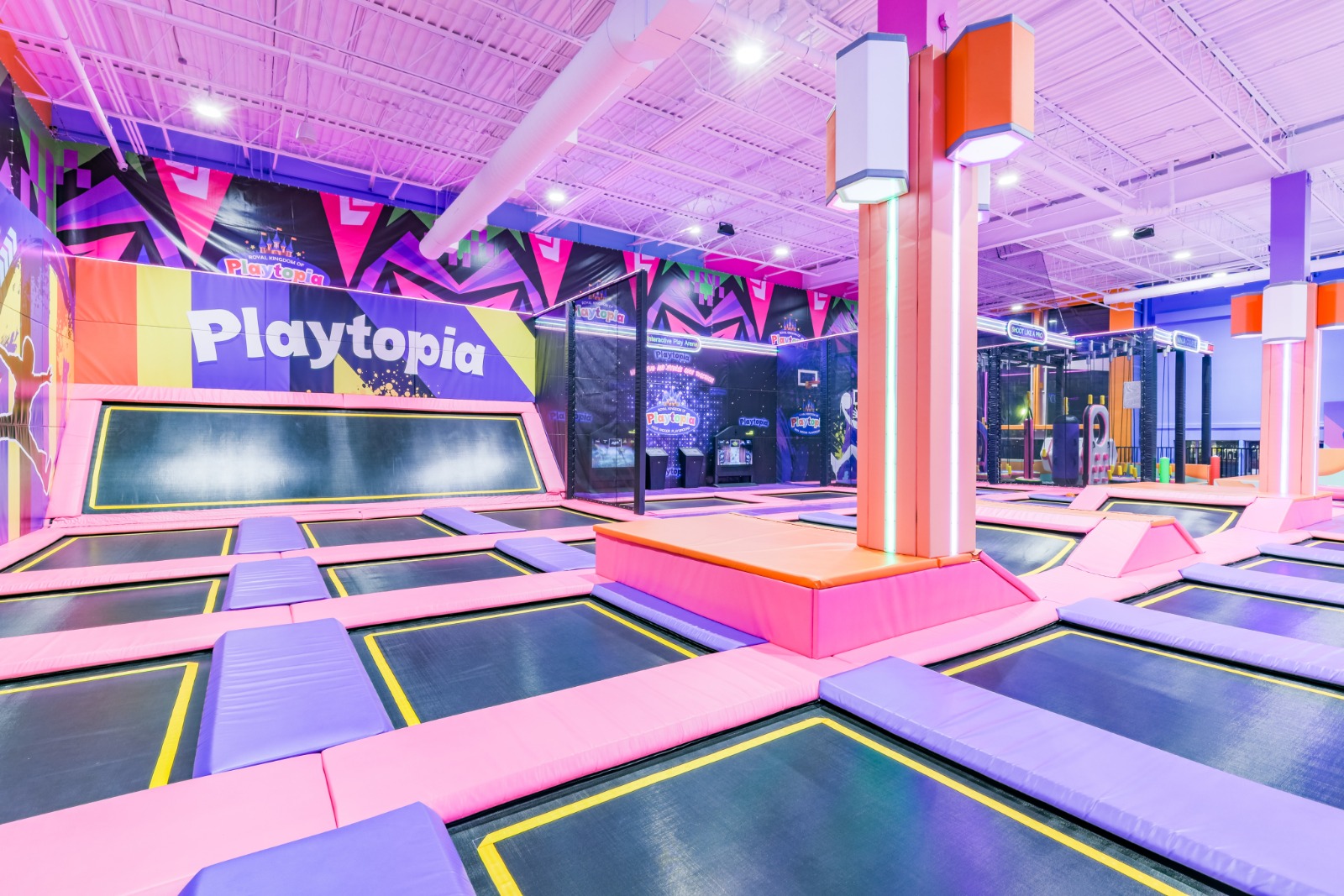 Purple and pink neon-lit indoor trampoline area.