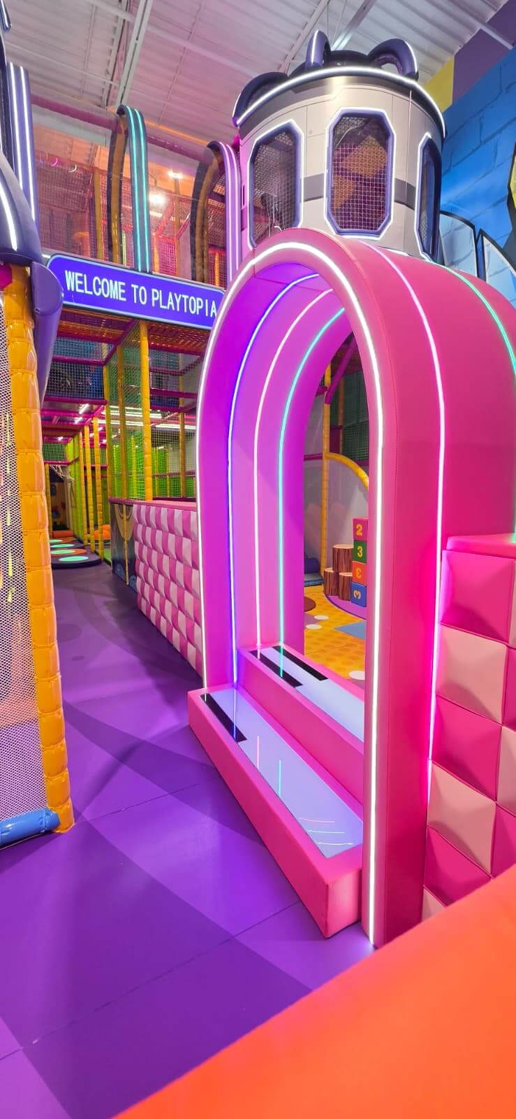 Enclosed toddler playscape pathway featuring a bright neon pink archway structure at Playtopia family center.